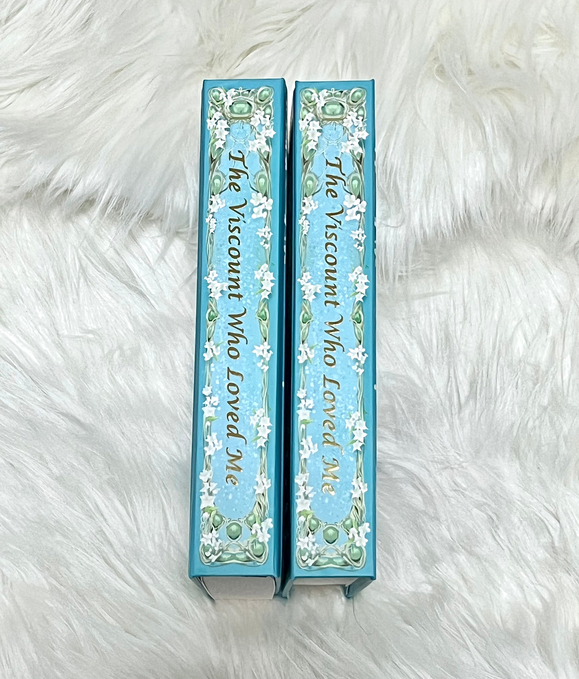 Two blue bookends with decorative text and floral patterns on a white fur background