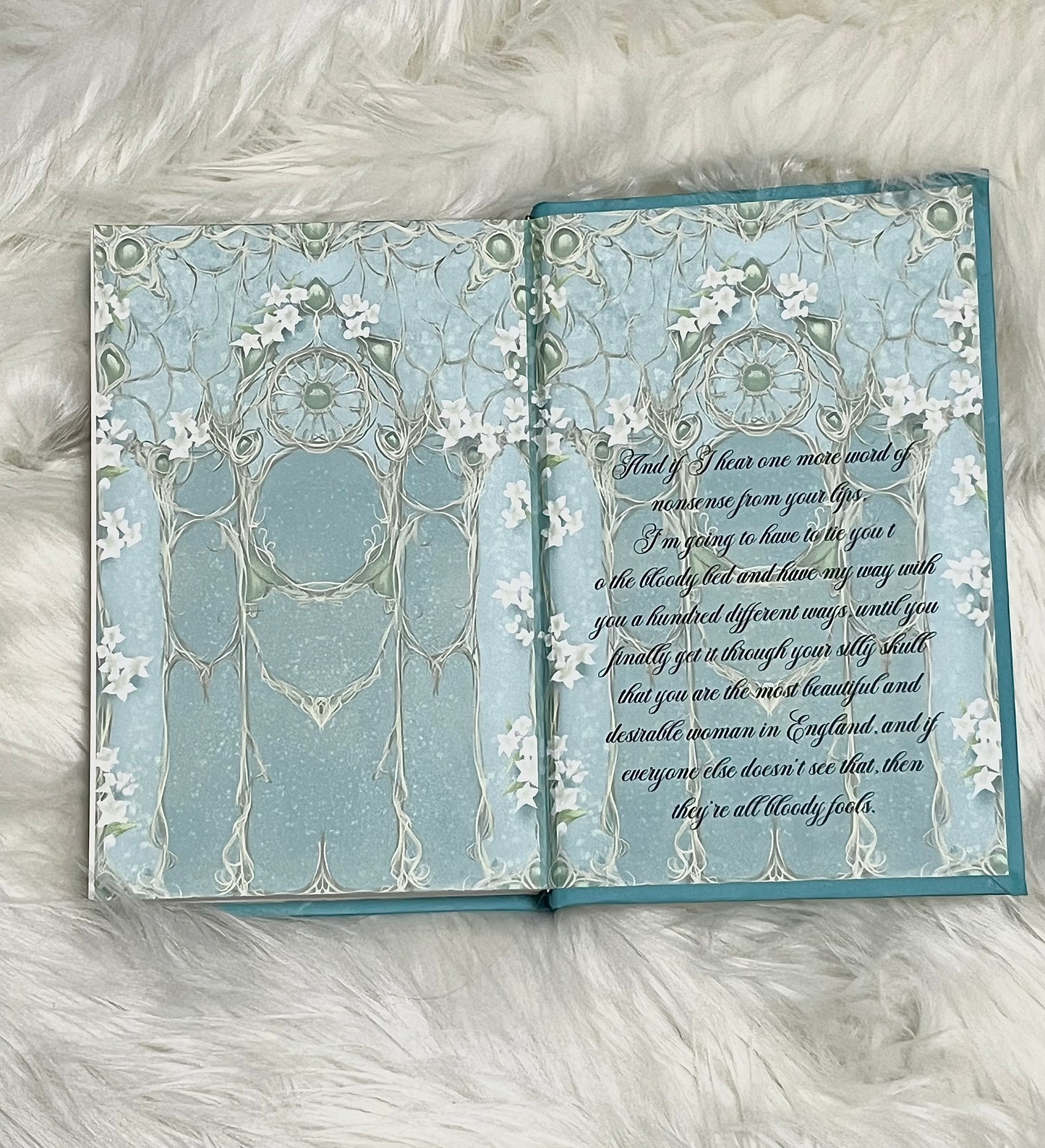 Open book with decorative pages on a fluffy white surface