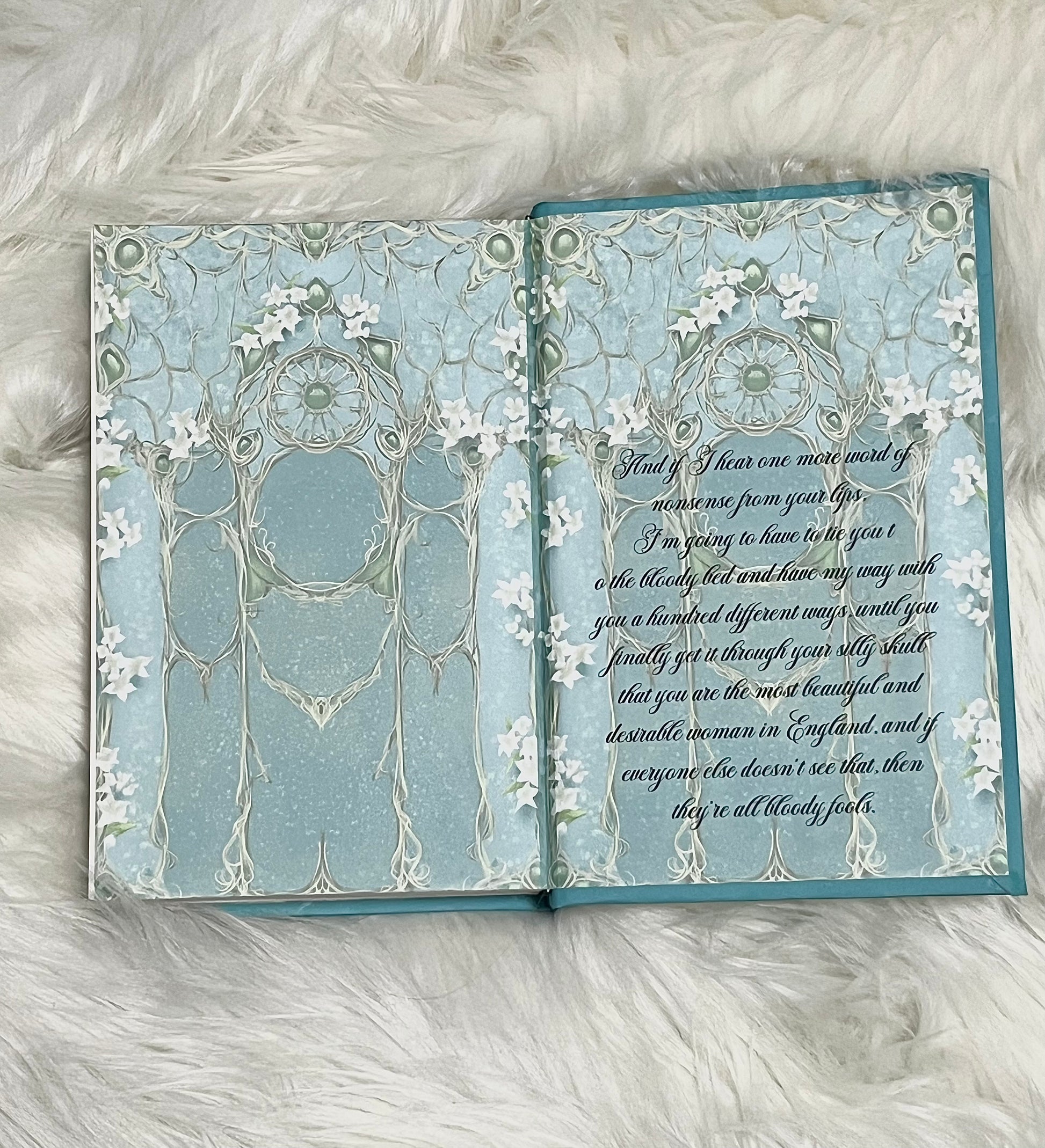Open book with decorative pages on a fluffy white surface